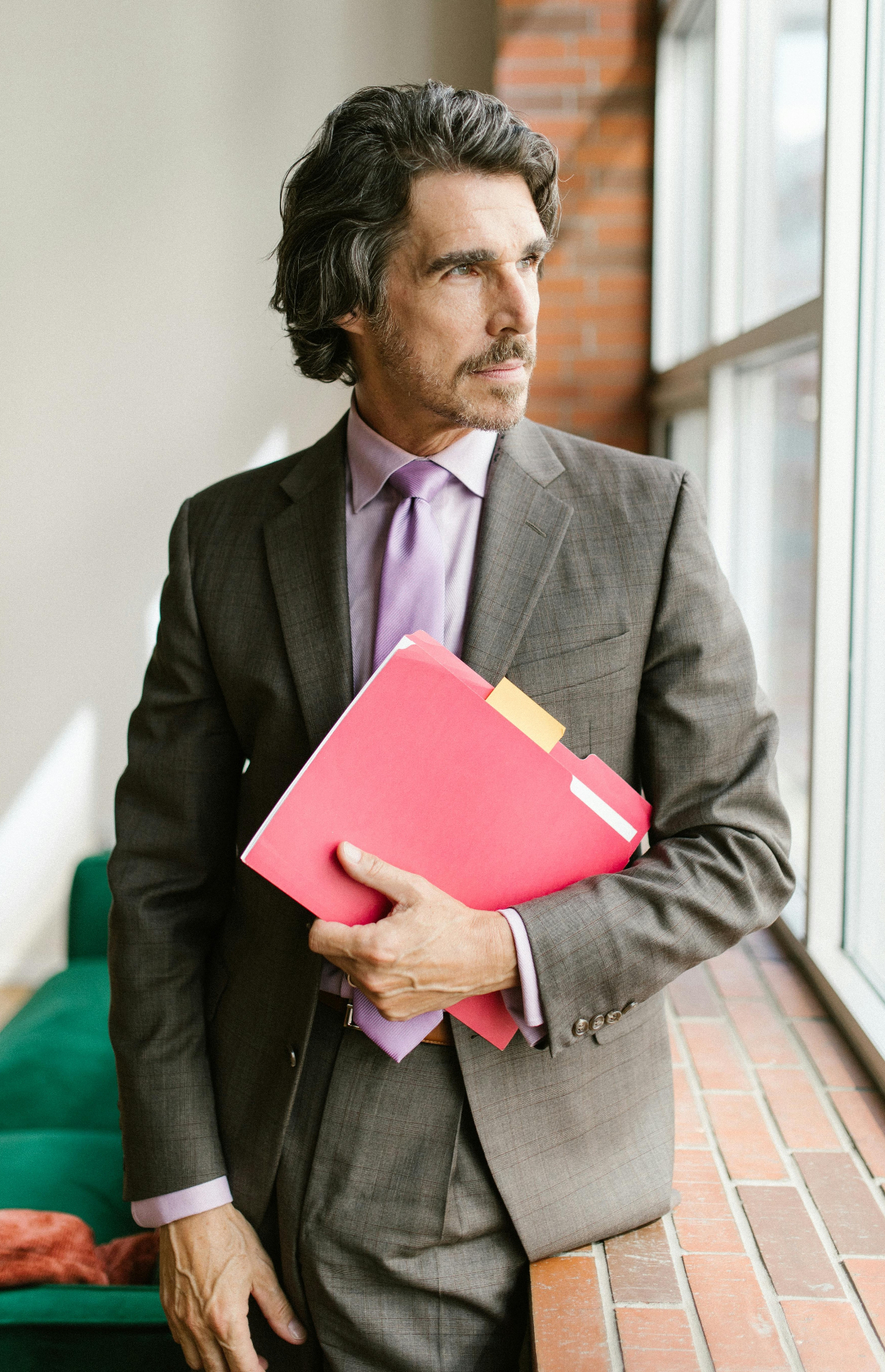 Senior professional holding a folder by a window
